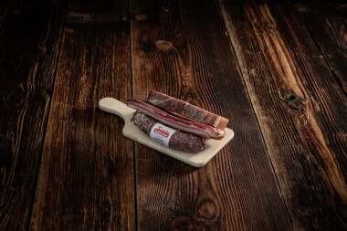 Bauernschinken, Rohess-Speck und eine Rohwurst auf Holzbrett Wurst Trockenfleisch Fleischtrockenerei Sialm Segnas Disentis Graubünden Tradition Spezialität Geschenk